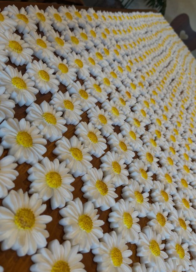 Centenas de sabonetes de margarida enfileirados sobre uma mesa de madeira