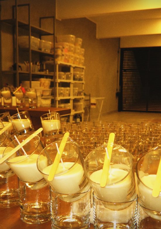 Velas recém-vertidas esfriando em copos de vidro no ateliê