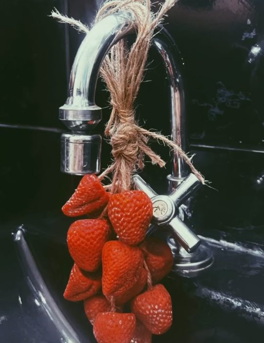 Cacho de sabonetes em forma de morango amarrado com juta e pendurado numa torneira
